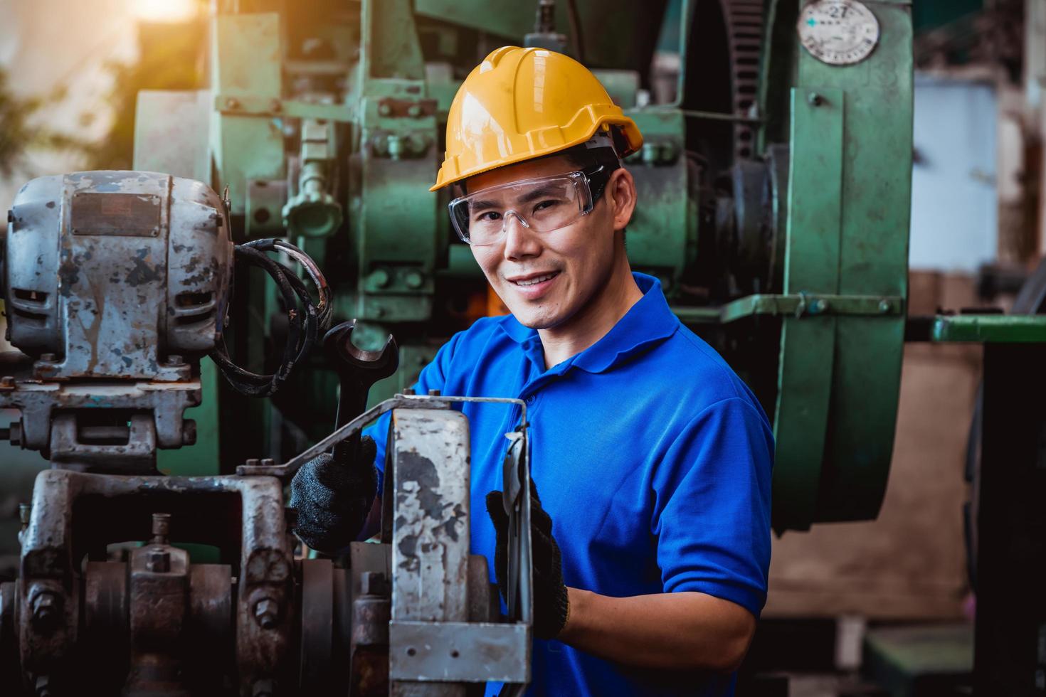 ingeniería industrial con control uniforme de seguridad que opera la máquina rectificadora de torno controlada por computadora que trabaja en la fábrica de la industria. foto