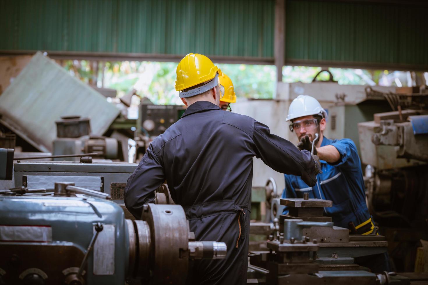 ingeniería industrial con control uniforme de seguridad que opera la máquina rectificadora de torno controlada por computadora que trabaja en la fábrica de la industria. foto