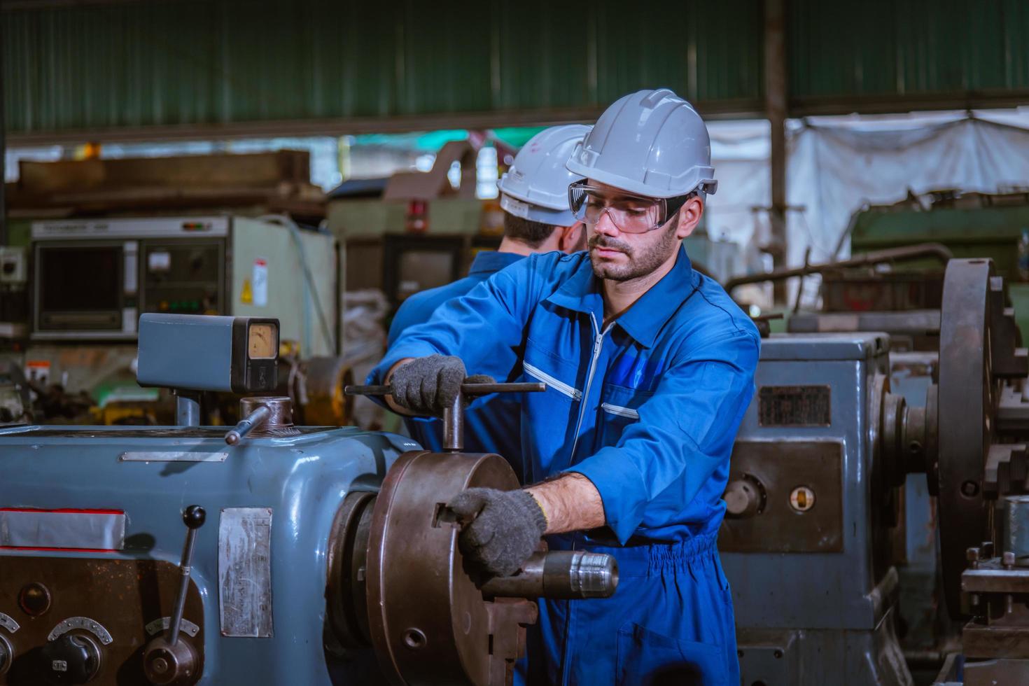 Industry engineering wearing safety uniform control operating computer controlled lathe grinding machine working in industry factory. photo