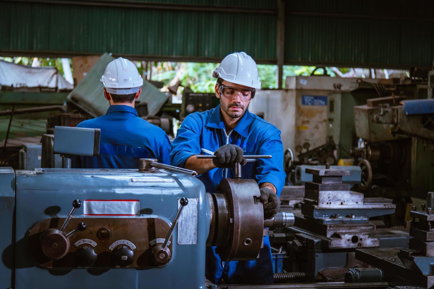 Industry engineering wearing safety uniform control operating computer controlled lathe grinding machine working in industry factory. photo