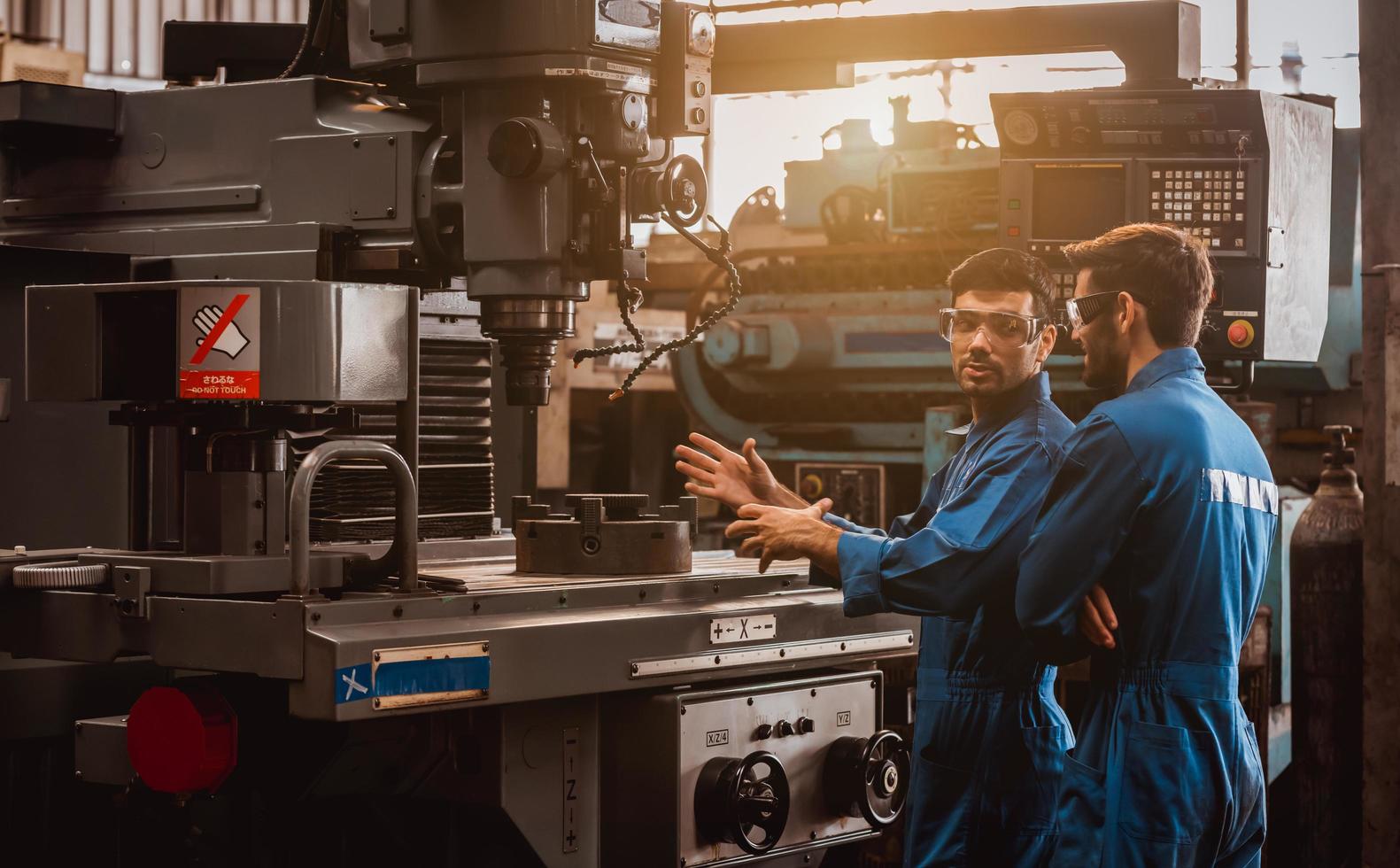Industry engineering wearing safety uniform control operating computer controlled lathe grinding machine working in industry factory. photo