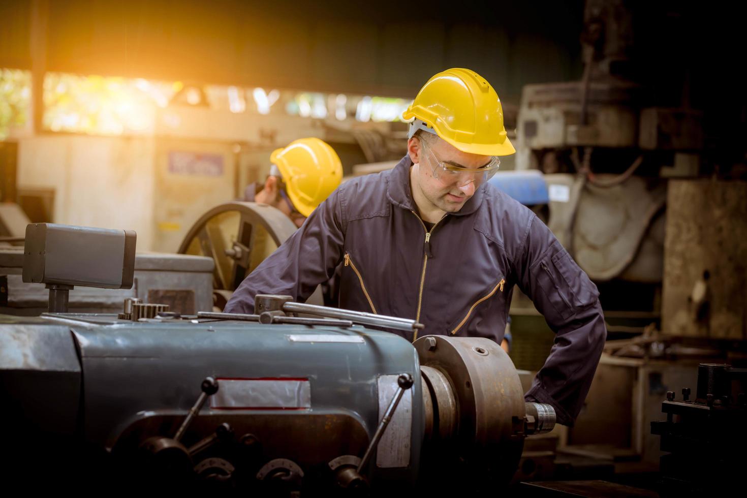 Industry engineering wearing safety uniform control operating computer controlled lathe grinding machine working in industry factory. photo