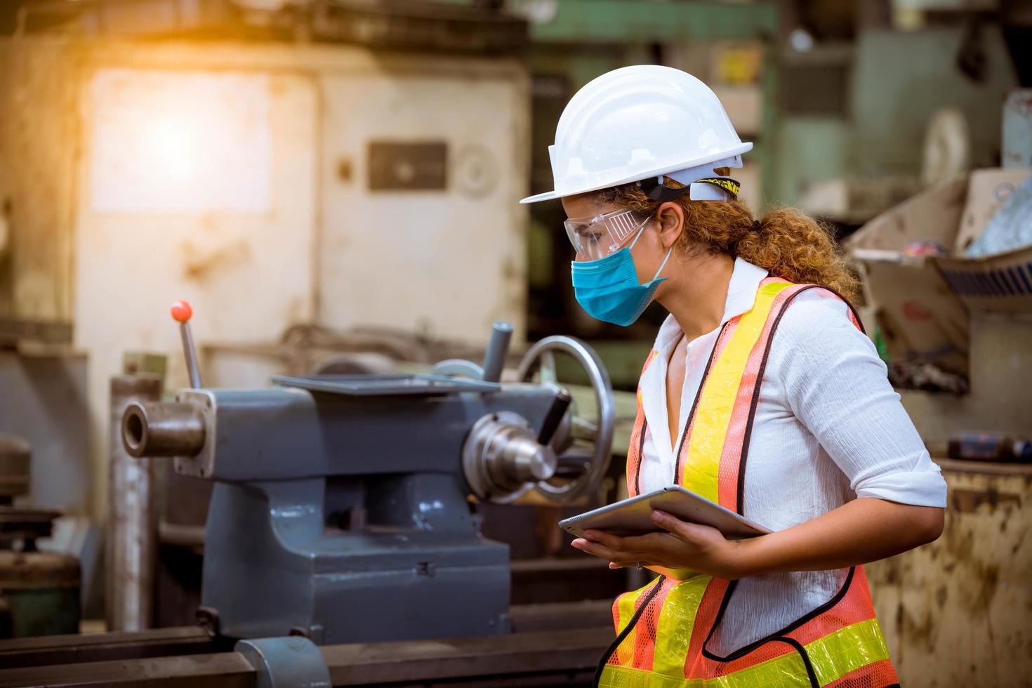 engineer under inspection and checking production process on factory station holding screwdriver by wearing safety mask to protect for pollution and virus in factory. photo