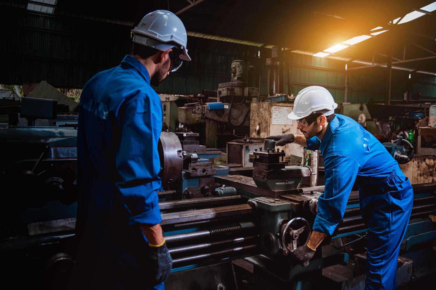 ingeniería industrial con control uniforme de seguridad que opera la máquina rectificadora de torno controlada por computadora que trabaja en la fábrica de la industria. foto