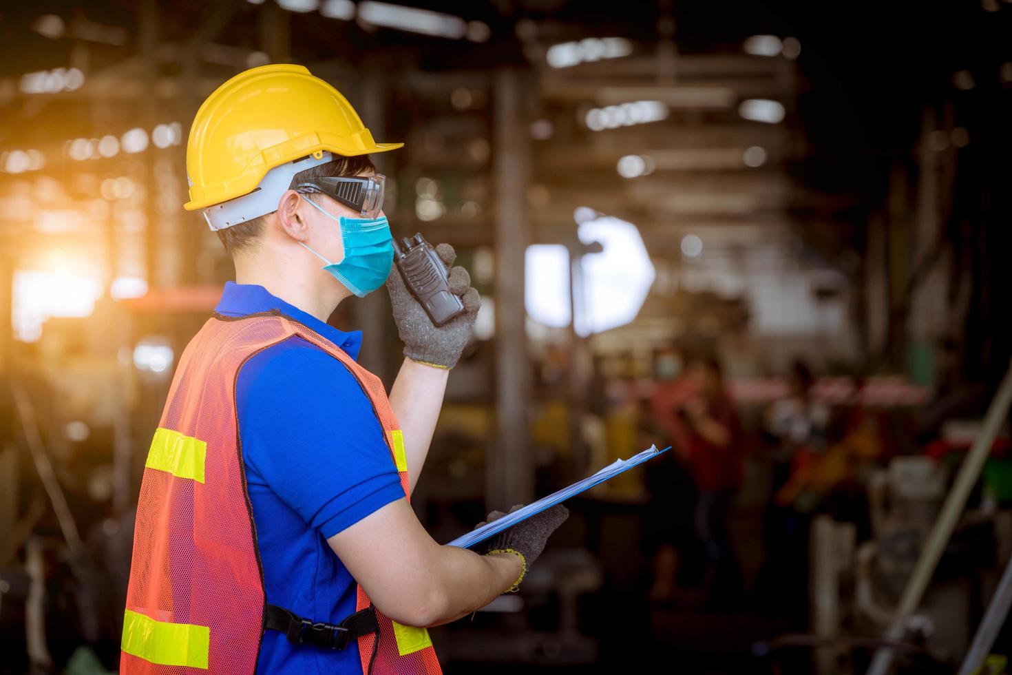 engineer under inspection and checking production process on factory station holding screwdriver by wearing safety mask to protect for pollution and virus in factory. photo