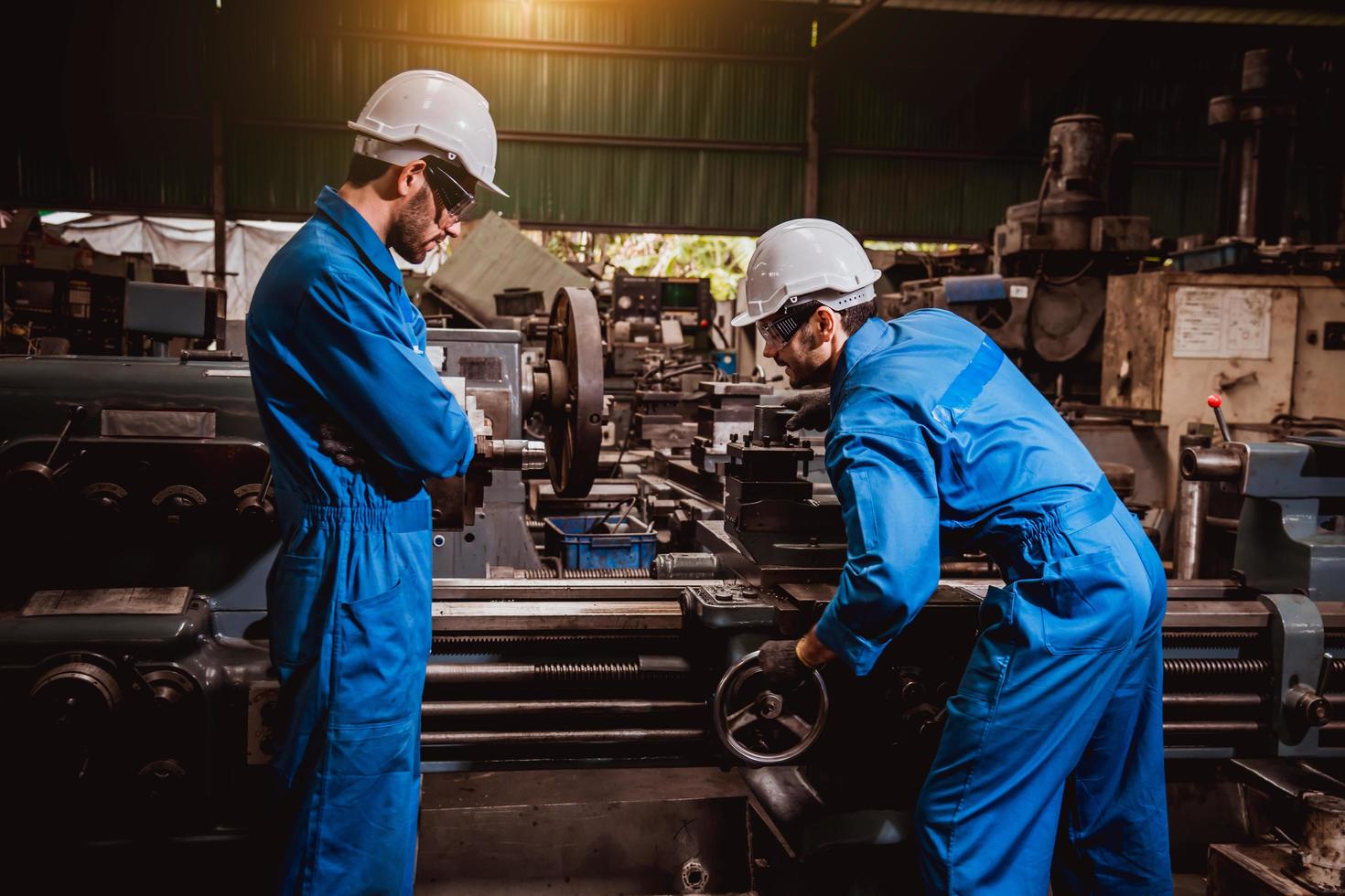 ingeniería industrial con control uniforme de seguridad que opera la máquina rectificadora de torno controlada por computadora que trabaja en la fábrica de la industria. foto