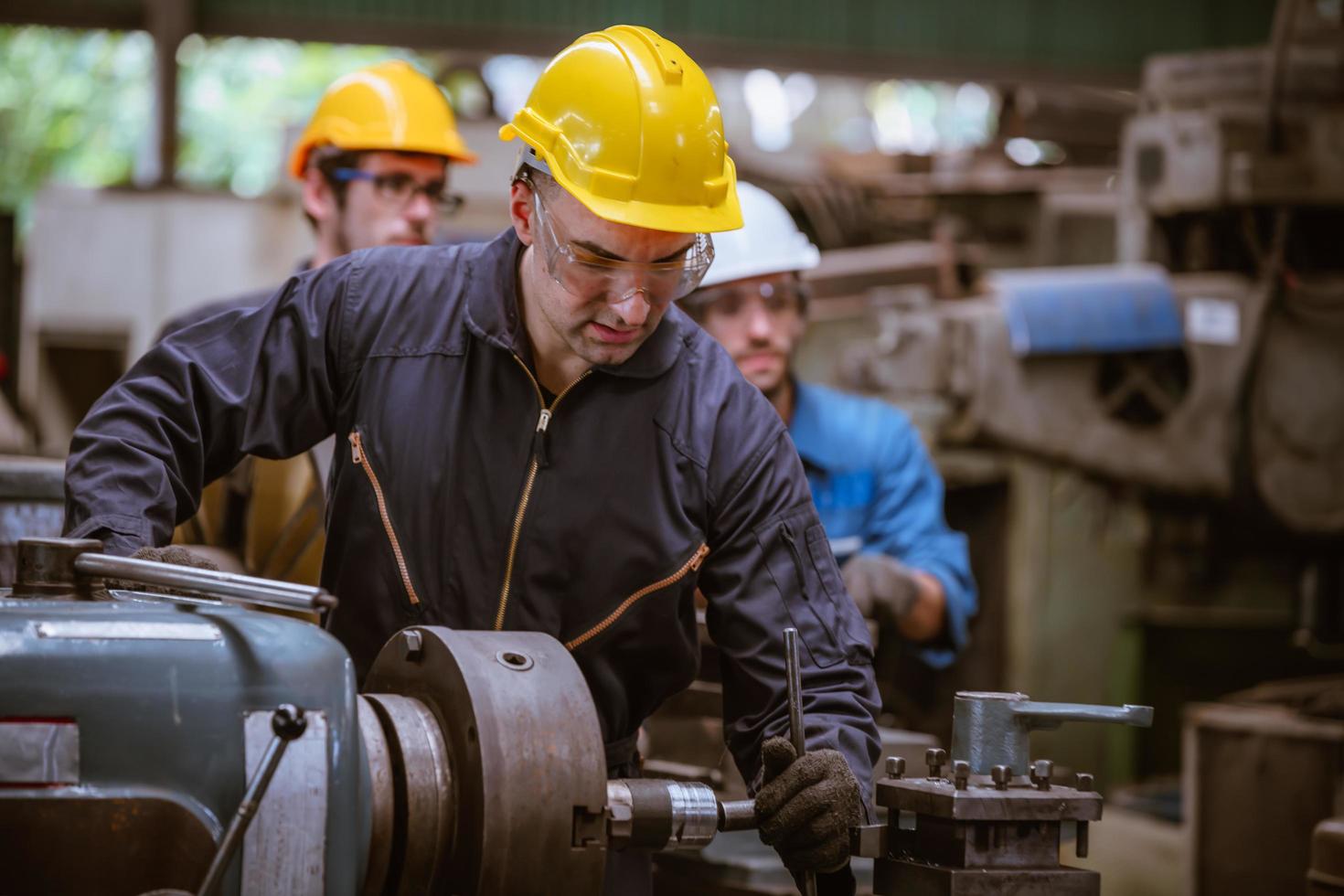 ingeniería industrial con control uniforme de seguridad que opera la máquina rectificadora de torno controlada por computadora que trabaja en la fábrica de la industria. foto