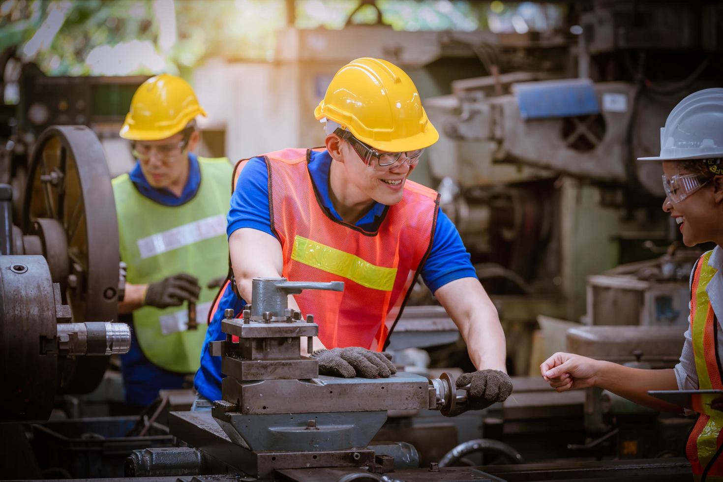 ingeniería industrial con control uniforme de seguridad que opera la máquina rectificadora de torno controlada por computadora que trabaja en la fábrica de la industria. foto