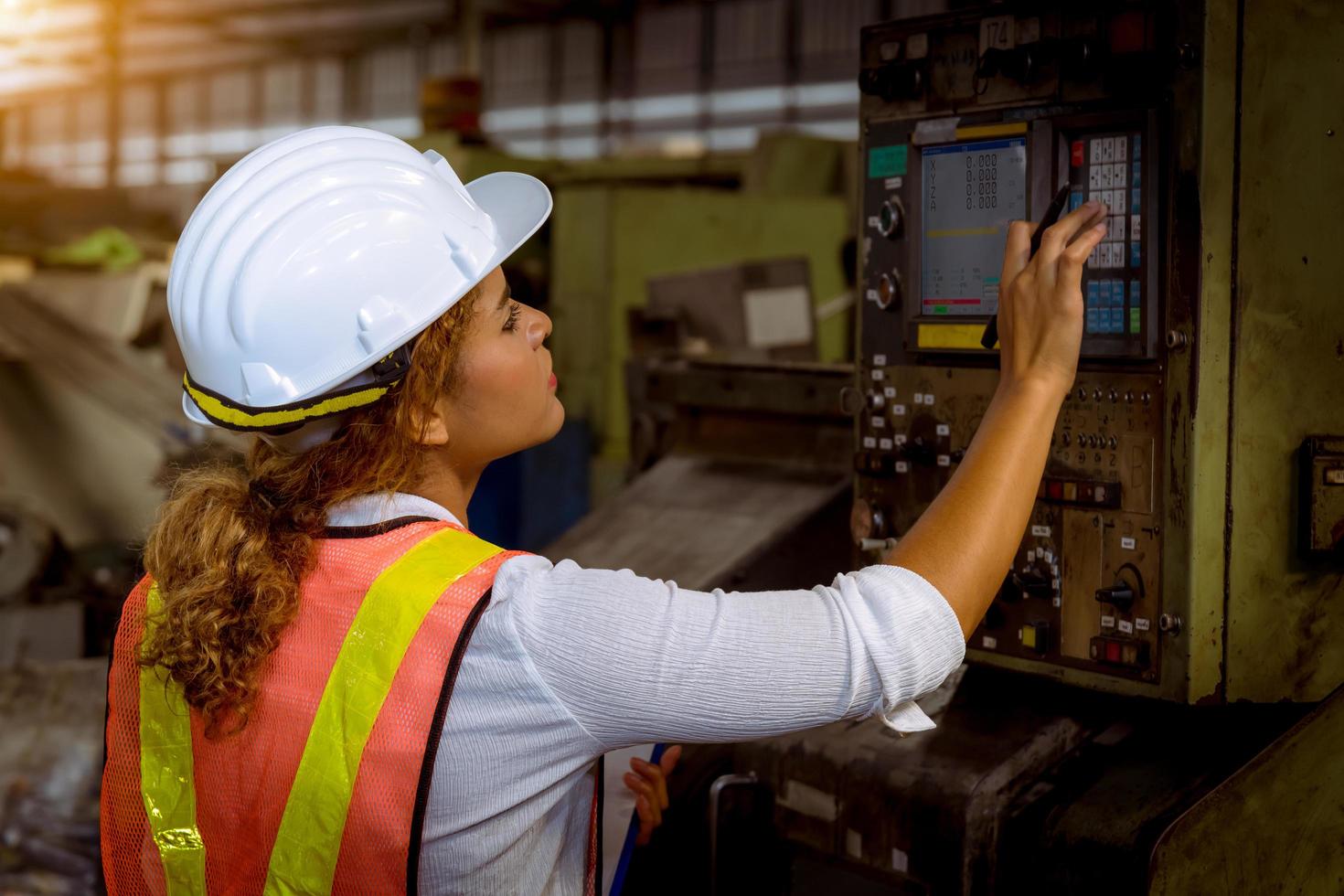 The Industry engineering wearing safety uniform control operating computer controlled lathe grinding machine working in industry factory. photo
