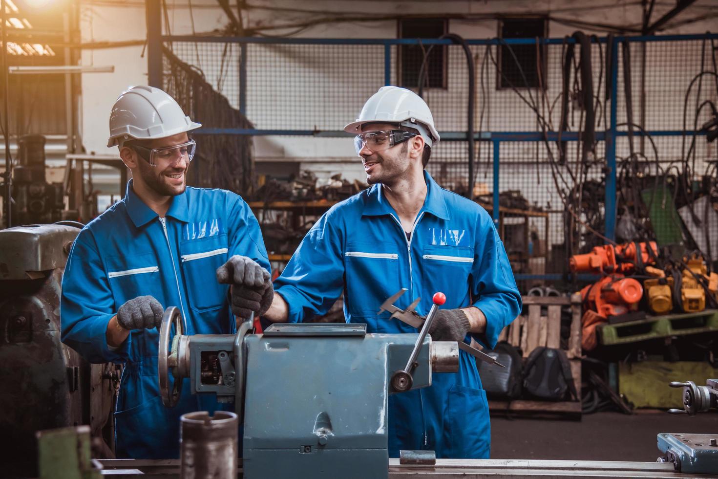 ingeniería industrial con control uniforme de seguridad que opera la máquina rectificadora de torno controlada por computadora que trabaja en la fábrica de la industria. foto