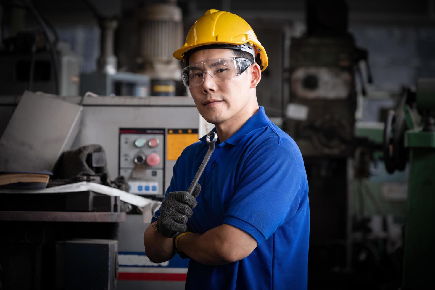 ingeniería industrial con control uniforme de seguridad que opera la máquina rectificadora de torno controlada por computadora que trabaja en la fábrica de la industria. foto