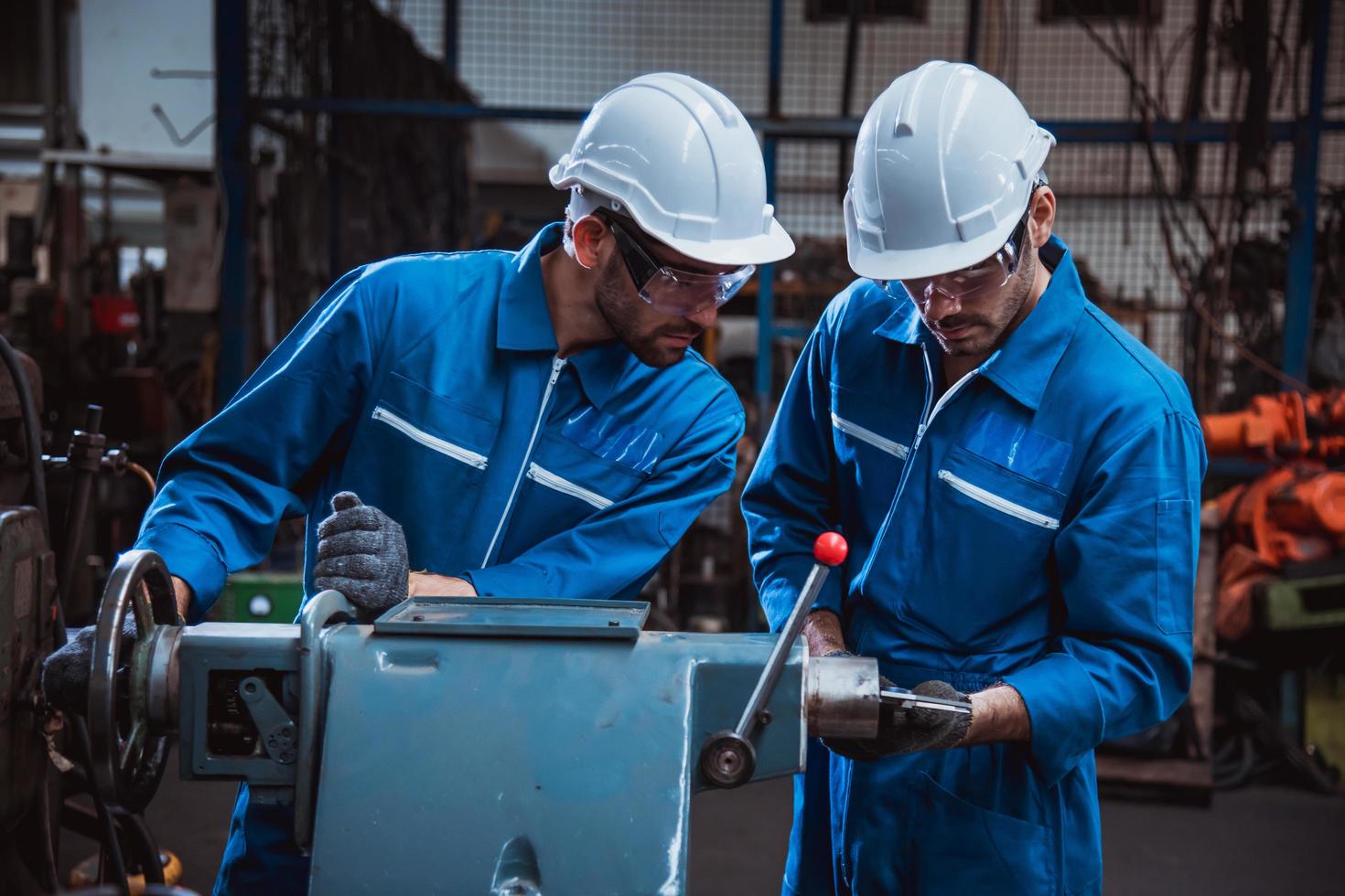 ingeniería industrial con control uniforme de seguridad que opera la máquina rectificadora de torno controlada por computadora que trabaja en la fábrica de la industria. foto