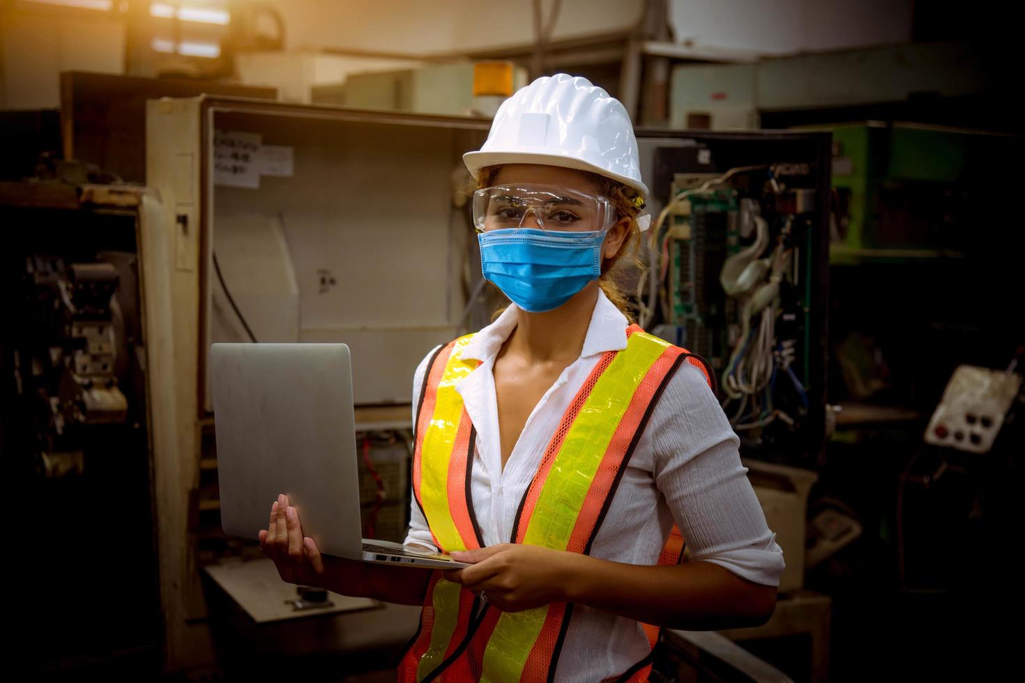 engineer under inspection and checking production process on factory station holding screwdriver by wearing safety mask to protect for pollution and virus in factory. photo