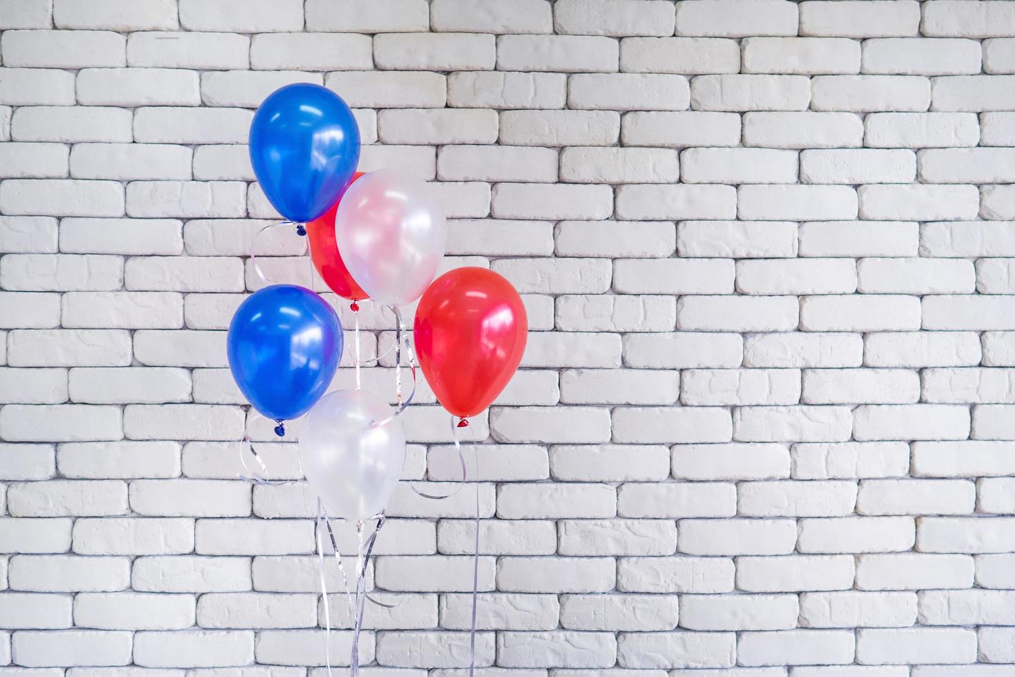 primer plano de globos multicolores contra el fondo de la pared de ladrillo blanco foto