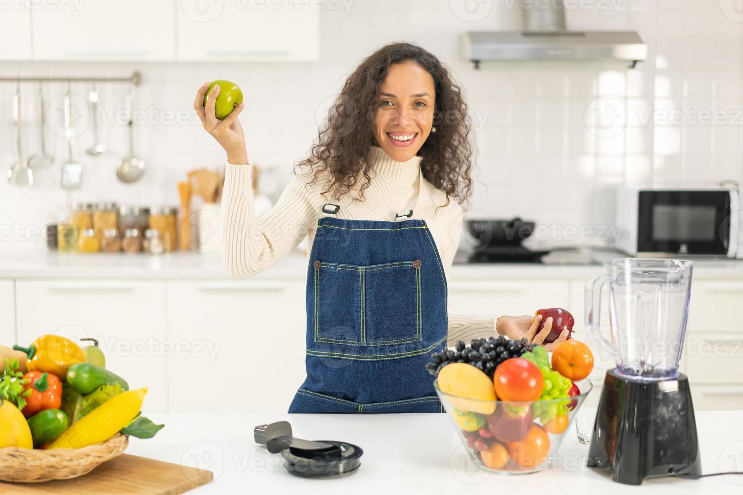 Latin woman making juice in kitchen photo