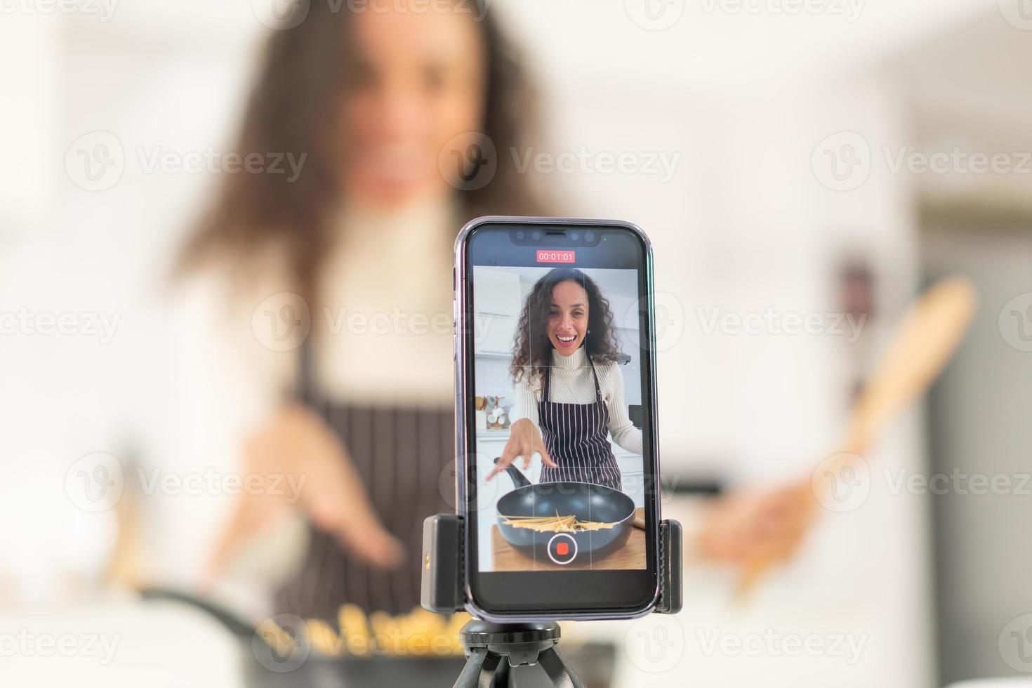 Latin woman shooting video and cooking at the kitchen photo