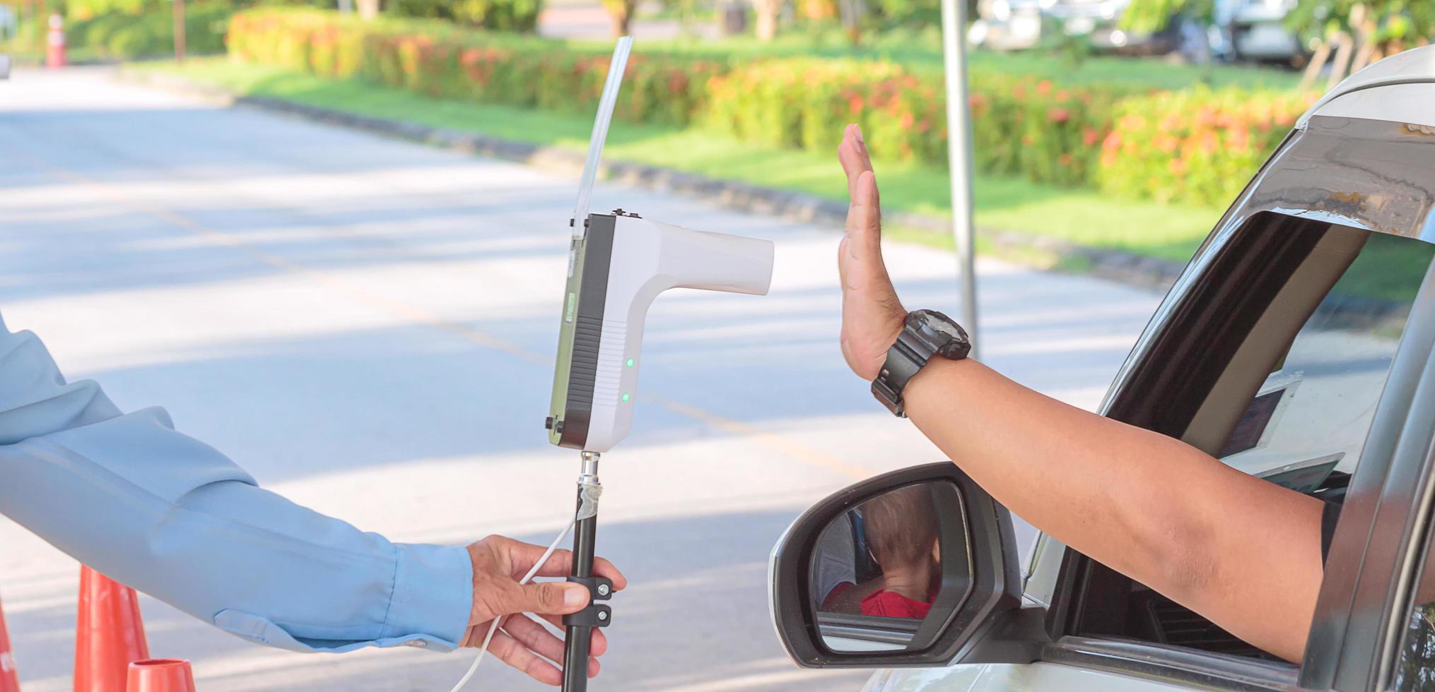 Security measures the driver's body temperature by using a thermometer to check the temperature. photo