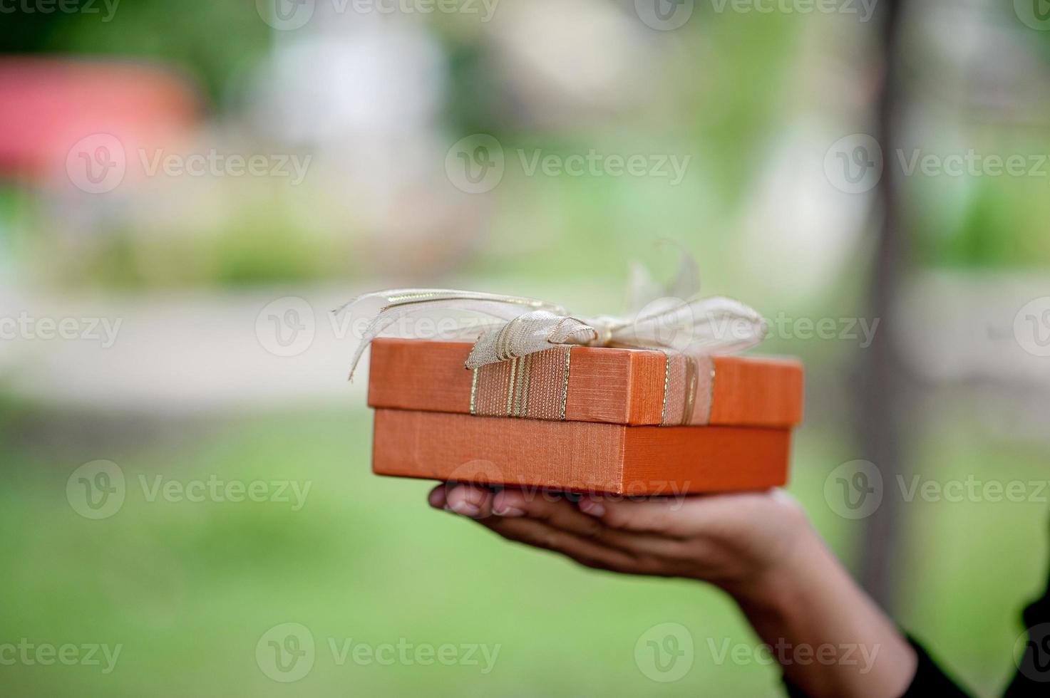 Hand and orange gift boxes give to your loved ones. Gift ideas photo