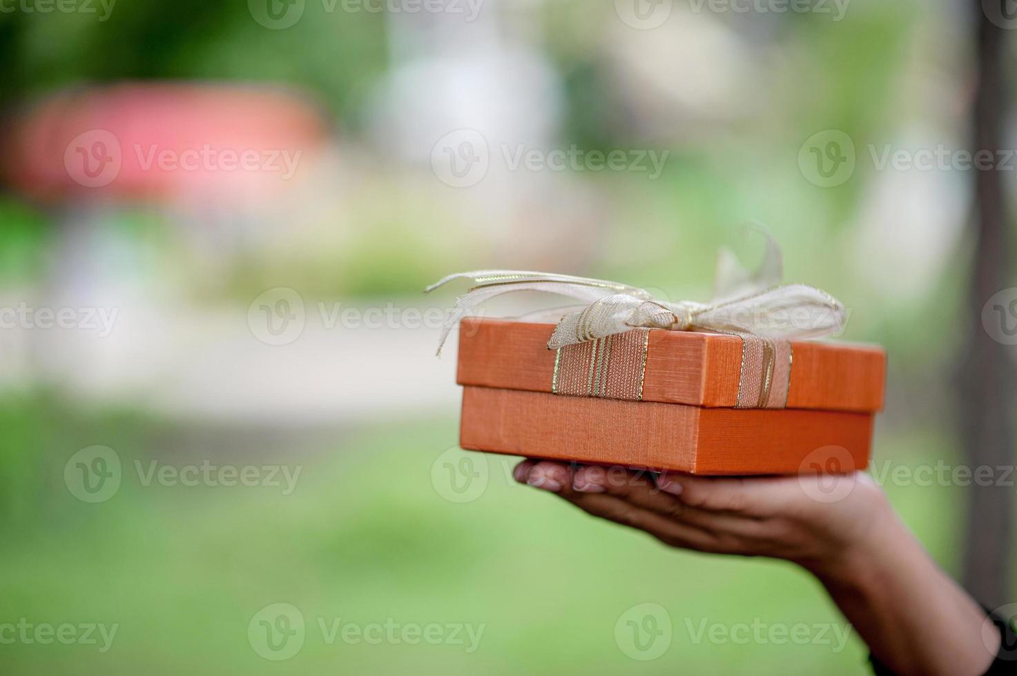 Hand and orange gift boxes give to your loved ones. Gift ideas photo