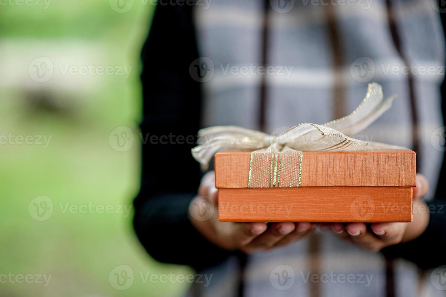 Hand and orange gift boxes give to your loved ones. Gift ideas photo