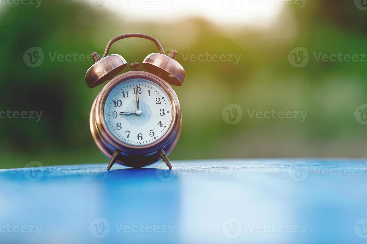 imagen de reloj de alarma dorada colocada en una mesa azul, concepto puntual de fondo verde con espacio de copia foto