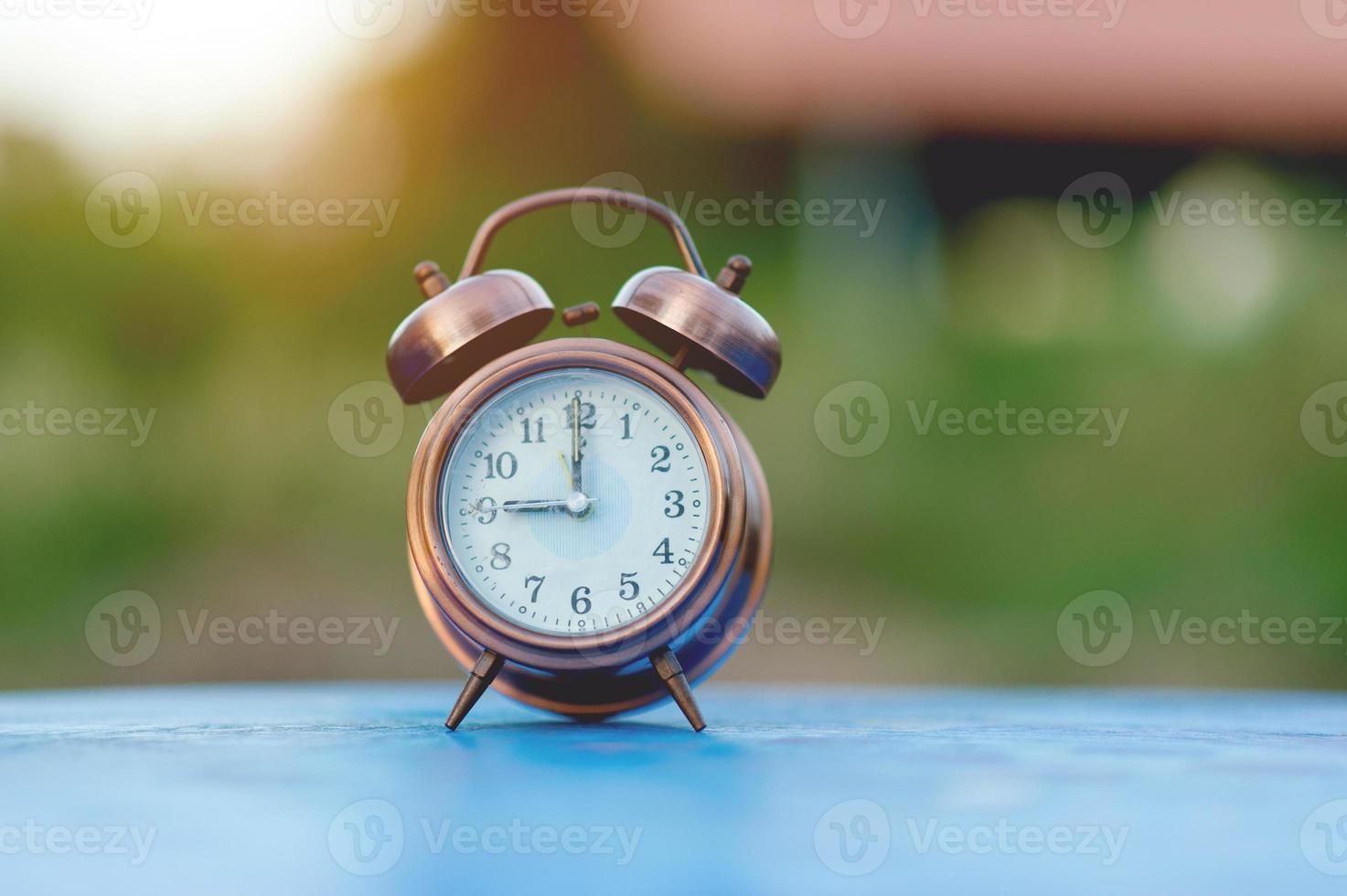 imagen de reloj de alarma dorada colocada en una mesa azul, concepto puntual de fondo verde con espacio de copia foto