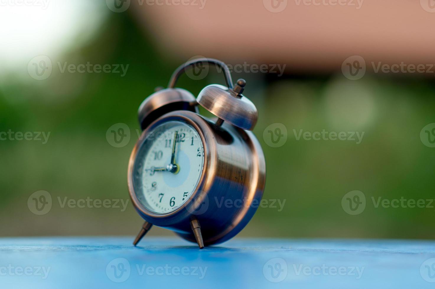 imagen de reloj de alarma dorada colocada en una mesa azul, concepto puntual de fondo verde con espacio de copia foto