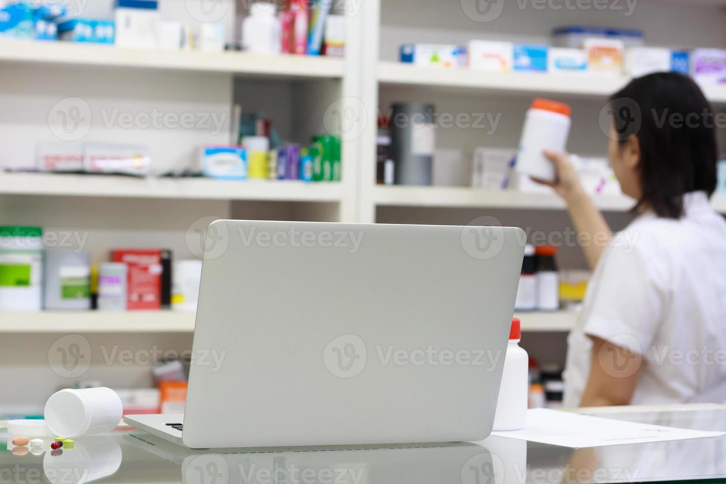 Pharmacist with laptop computer and medication in the pharmacy photo