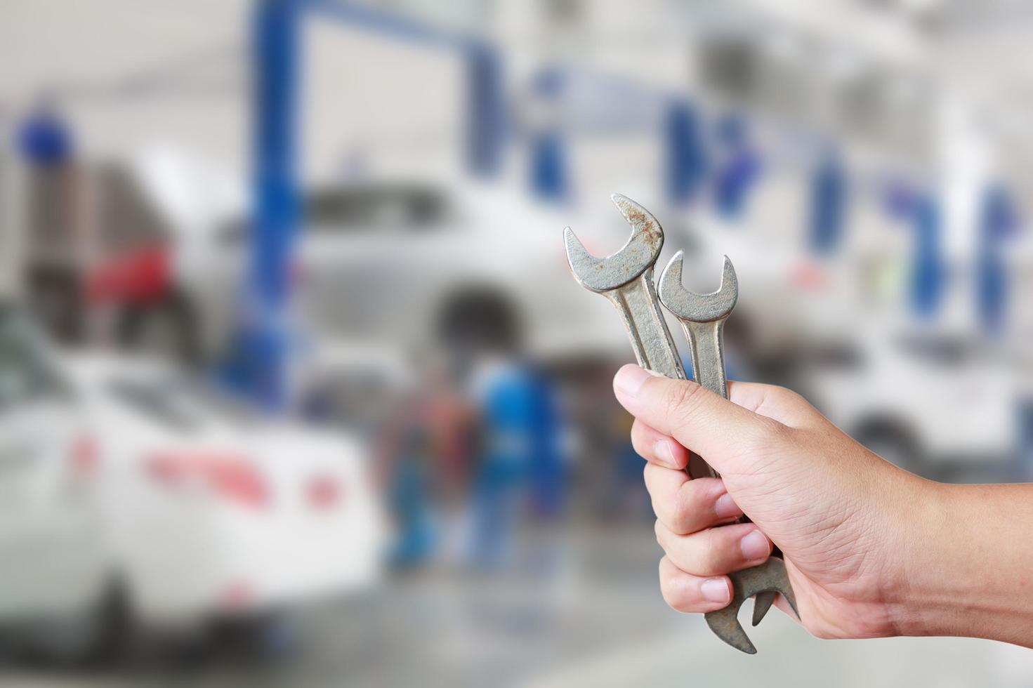 Technician holding a wrench with car repair service center background photo