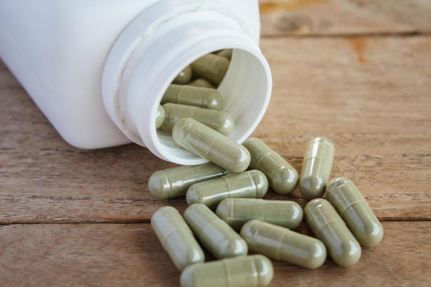 Herbal capsules spilling out of a bottle photo