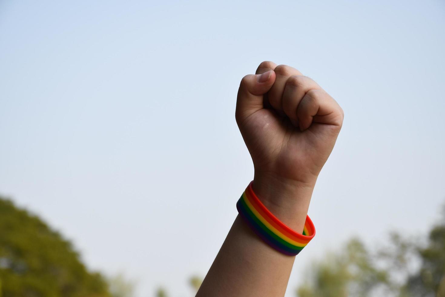 Rainbow wristbands in wrists of asian boy couple with blurred background, concept for celebration of lgbt community in pride month or in June around the world photo
