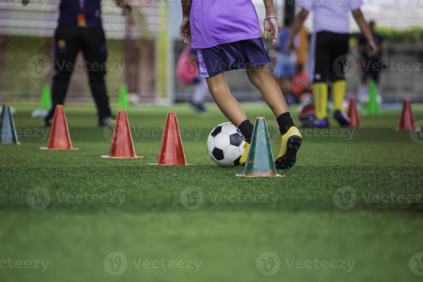 niños jugando tácticas de pelota de fútbol de control en el campo de hierba para entrenar foto