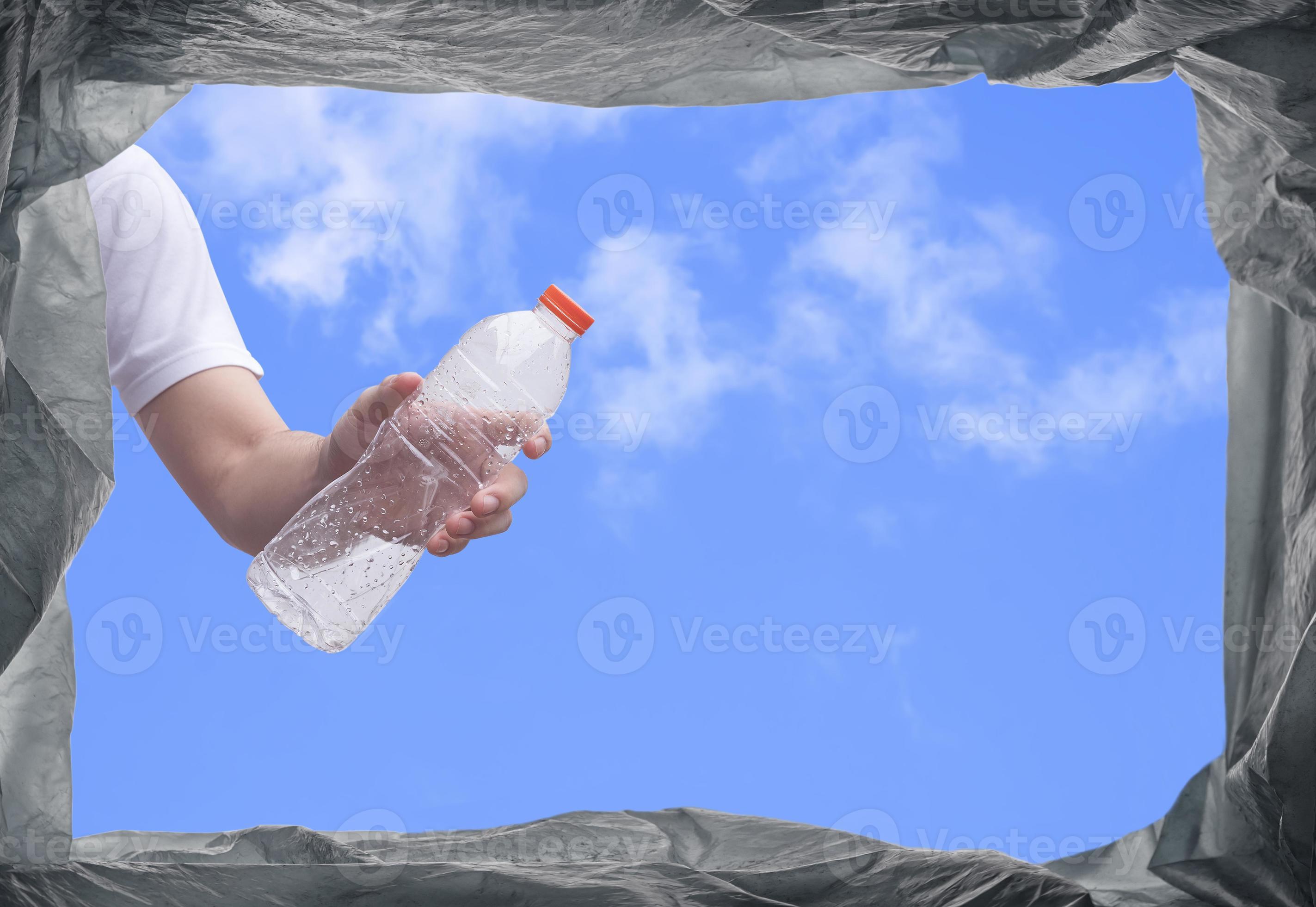 View from below of young man hand throwing plastic water bottle into