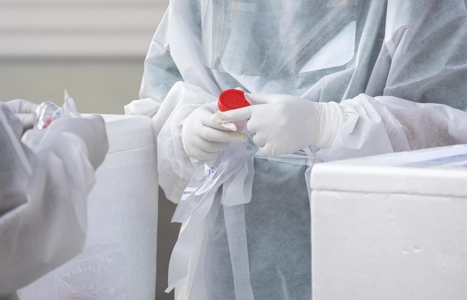 Focus at health worker's hand is collecting sputum and saliva samples to detect covid-19 infectious patients in public area photo