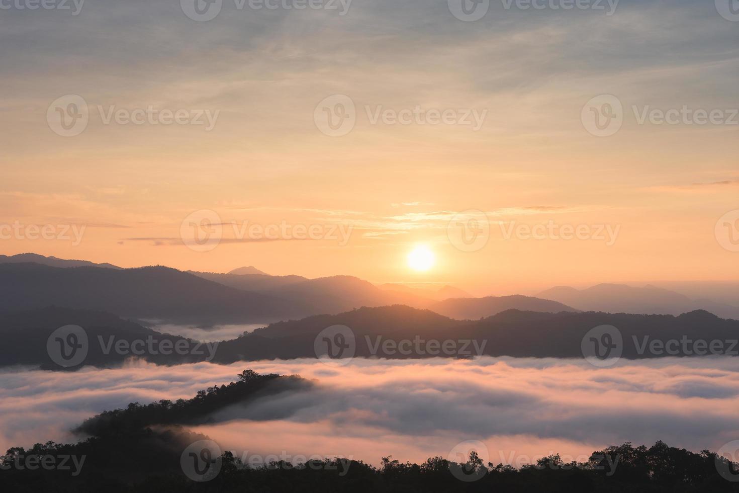 sunrise over large mountains and mist over forest in winter photo