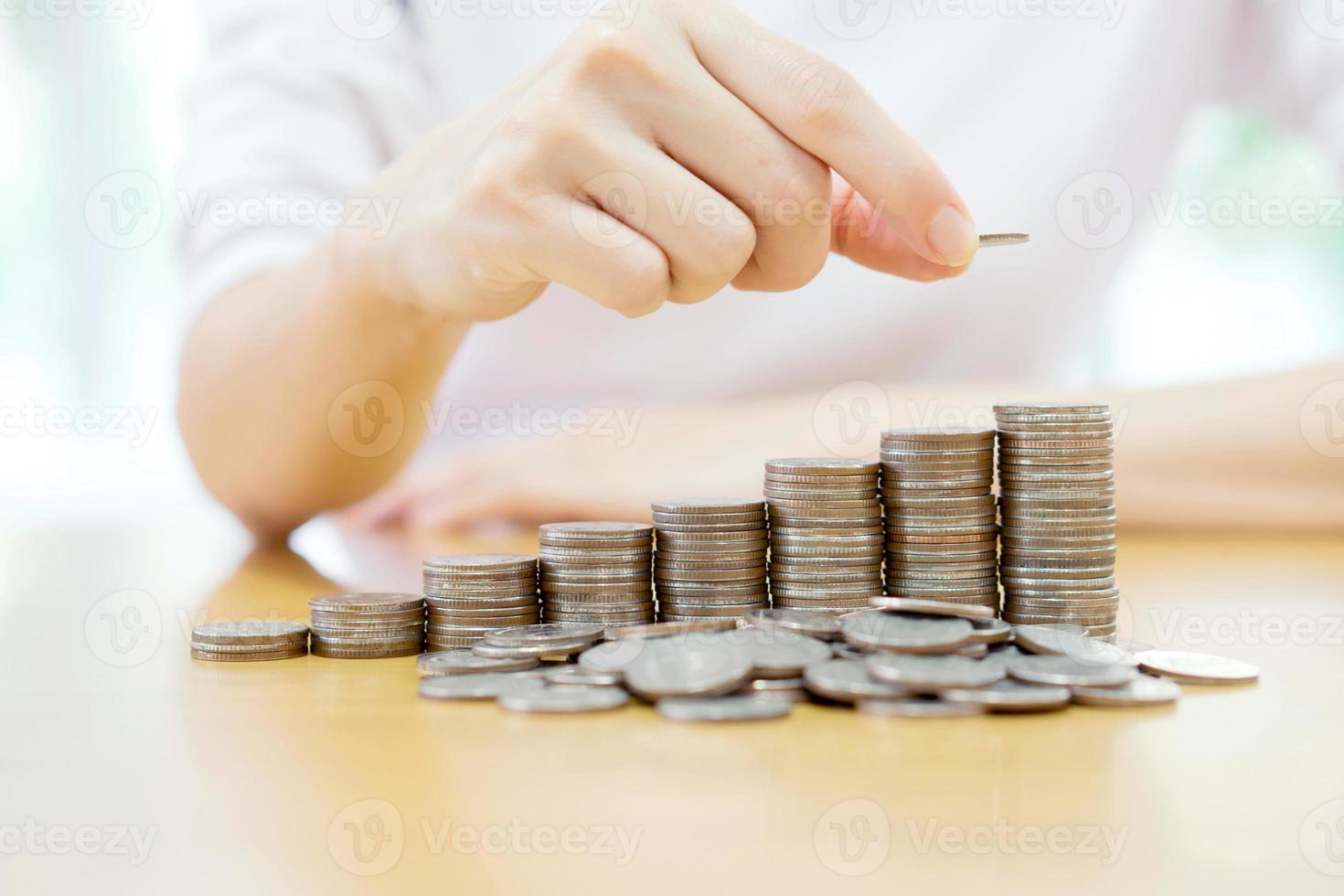 Close-up Of woman Hand Put Coins To Stack Of Coins photo