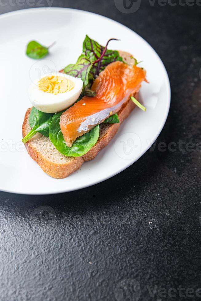 sándwich salmón huevo smorrebrod, mezcla de ensalada verde, tostada de pan de cereal mariscos foto
