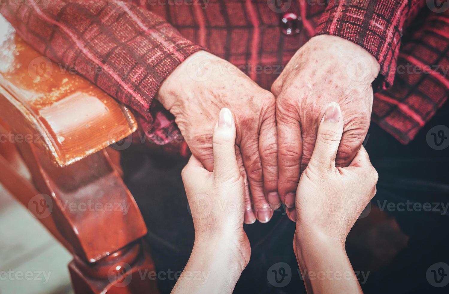 Teenage asia young girl carer holding grandma hands, concept of helping care for the elderly life with dark background, close up, copy space, cropped view photo