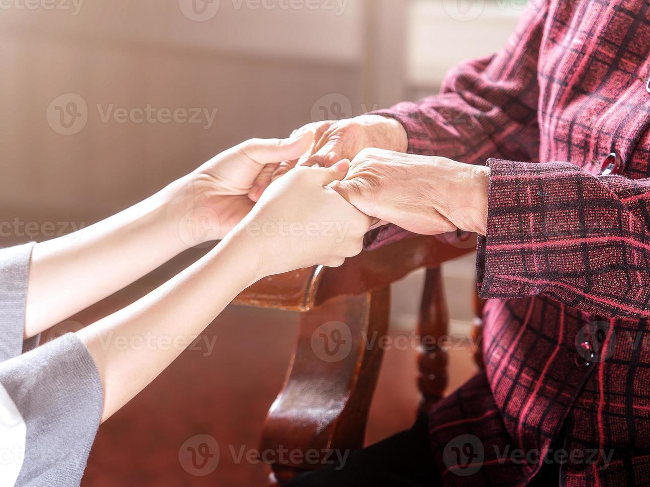 Teenage asia young girl carer holding grandma hands, concept of helping care for the elderly life with dark background, close up, copy space, cropped view photo