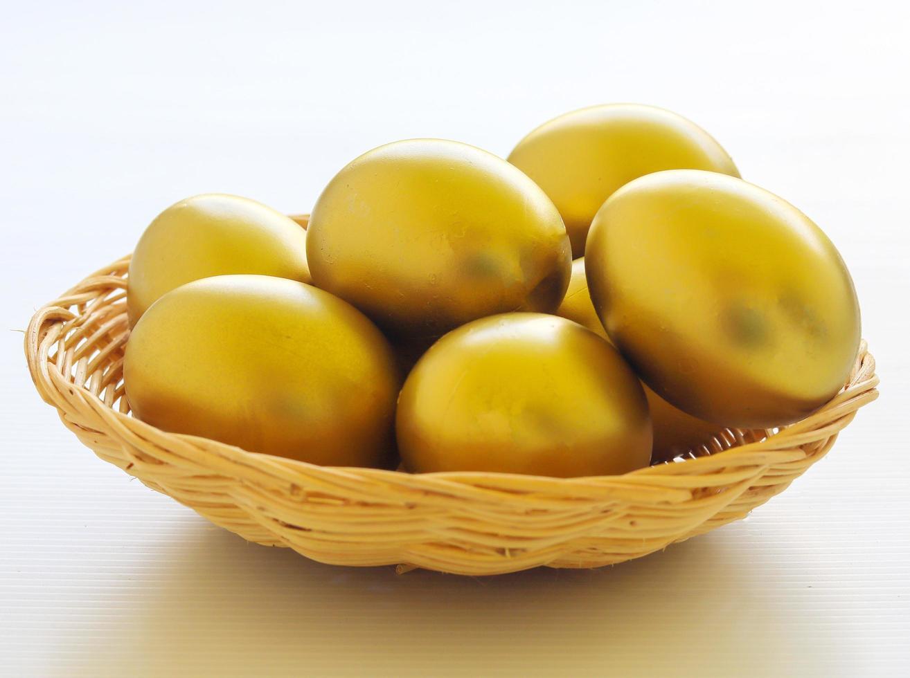 canasta de huevos de oro sobre un fondo blanco para pascua foto