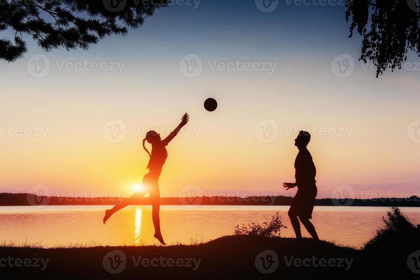 pareja jugando al atardecer junto al lago foto