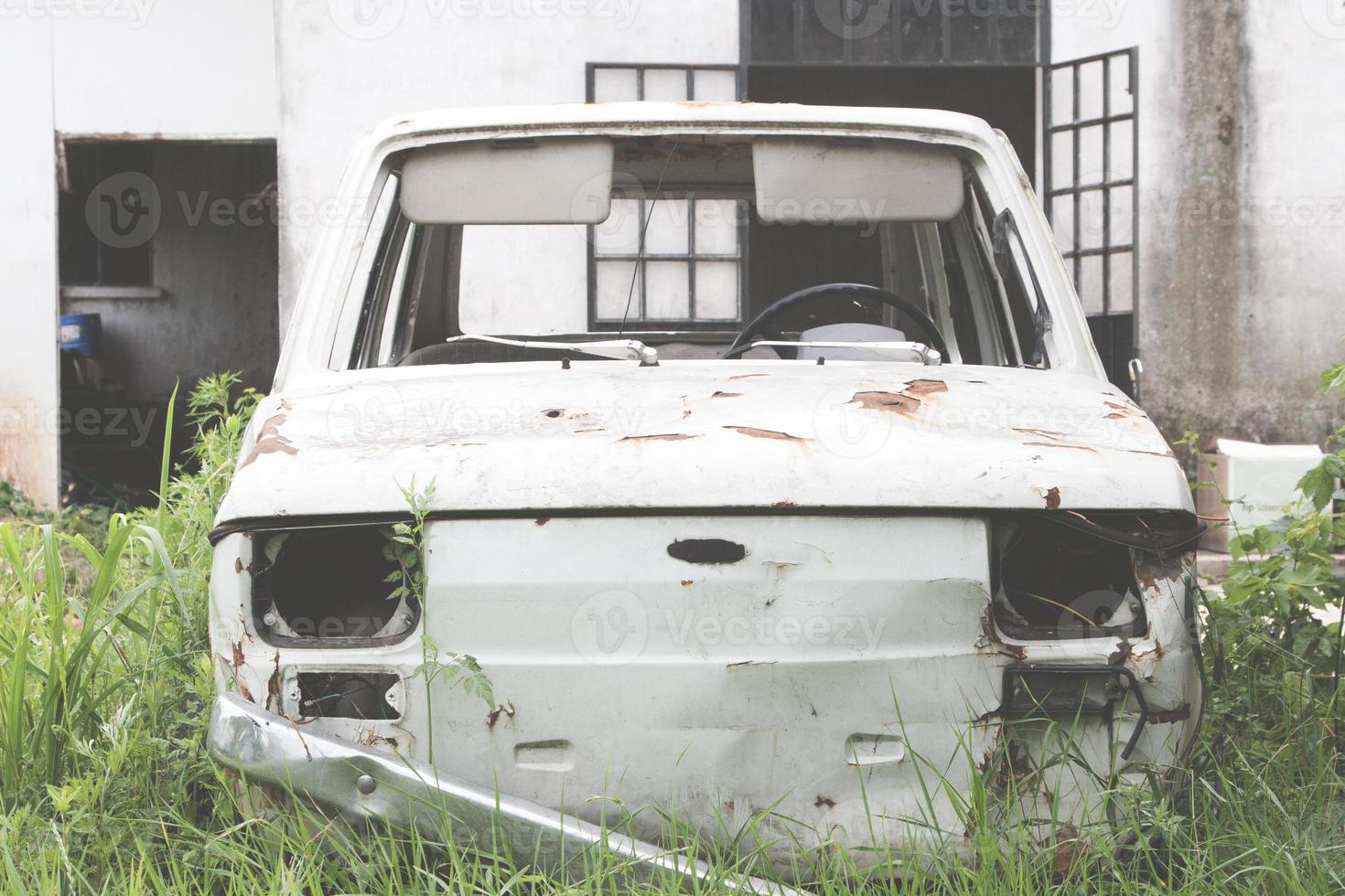 Old abandoned car rusting in the tall green grass. photo