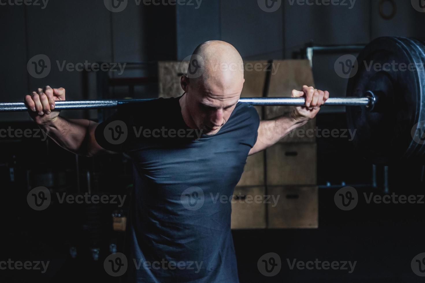 Athletic Muscular Man Holding Barbell On Your Shoulders In Gym. Dramatic Color Grading. photo