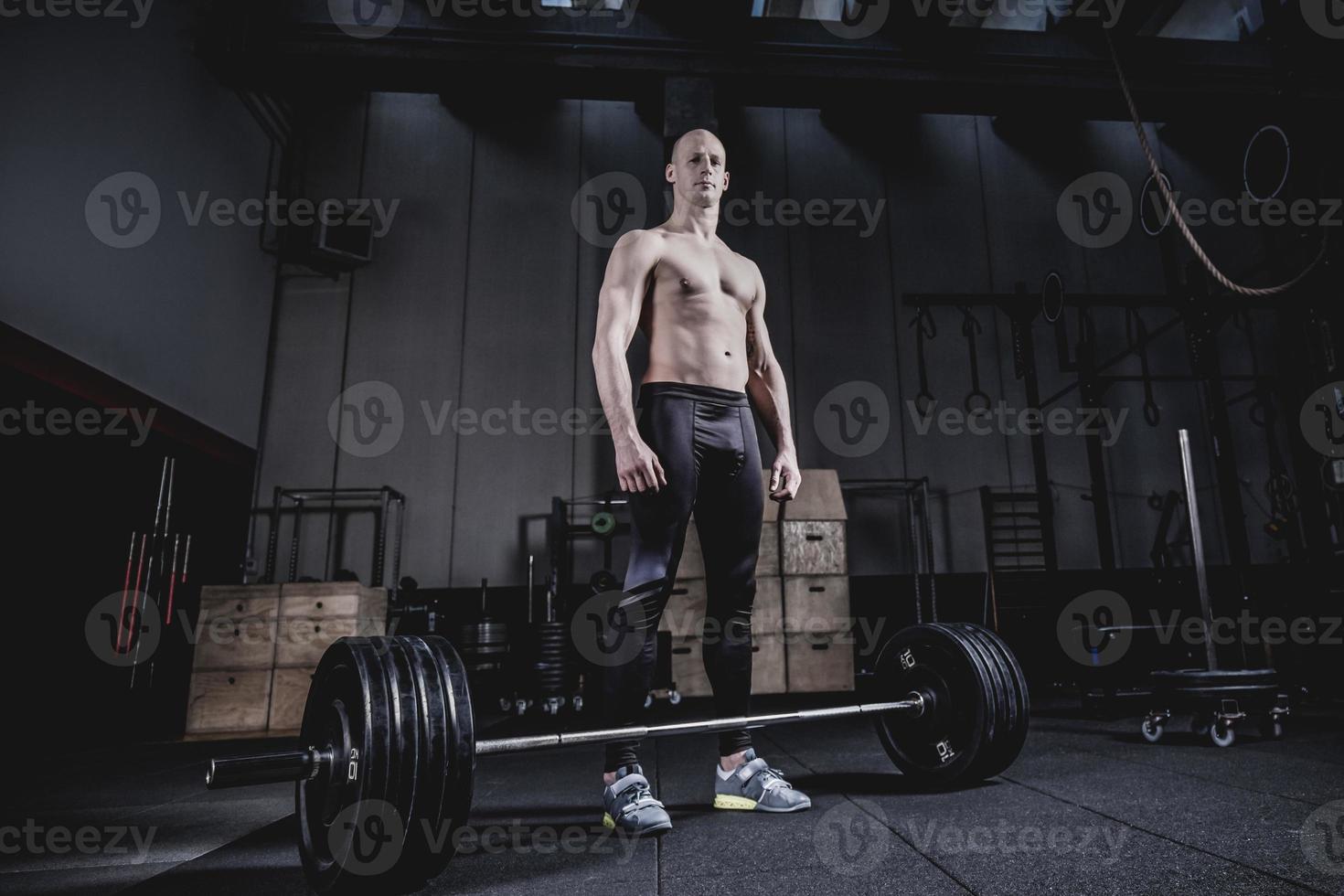 Muscular man Standing at Barbells Before Exercise. Dramatic Color Grading. photo
