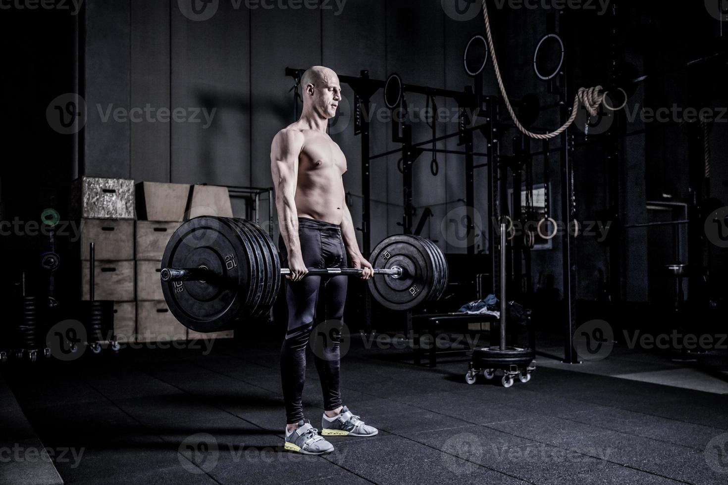 Muscular Man Doing Heavy Deadlift Exercise. Dramatic color grading. photo