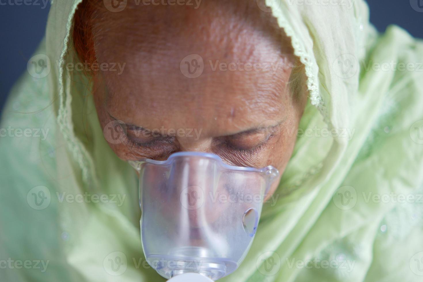 mujeres mayores que usan nebulizador contra un fondo gris claro foto