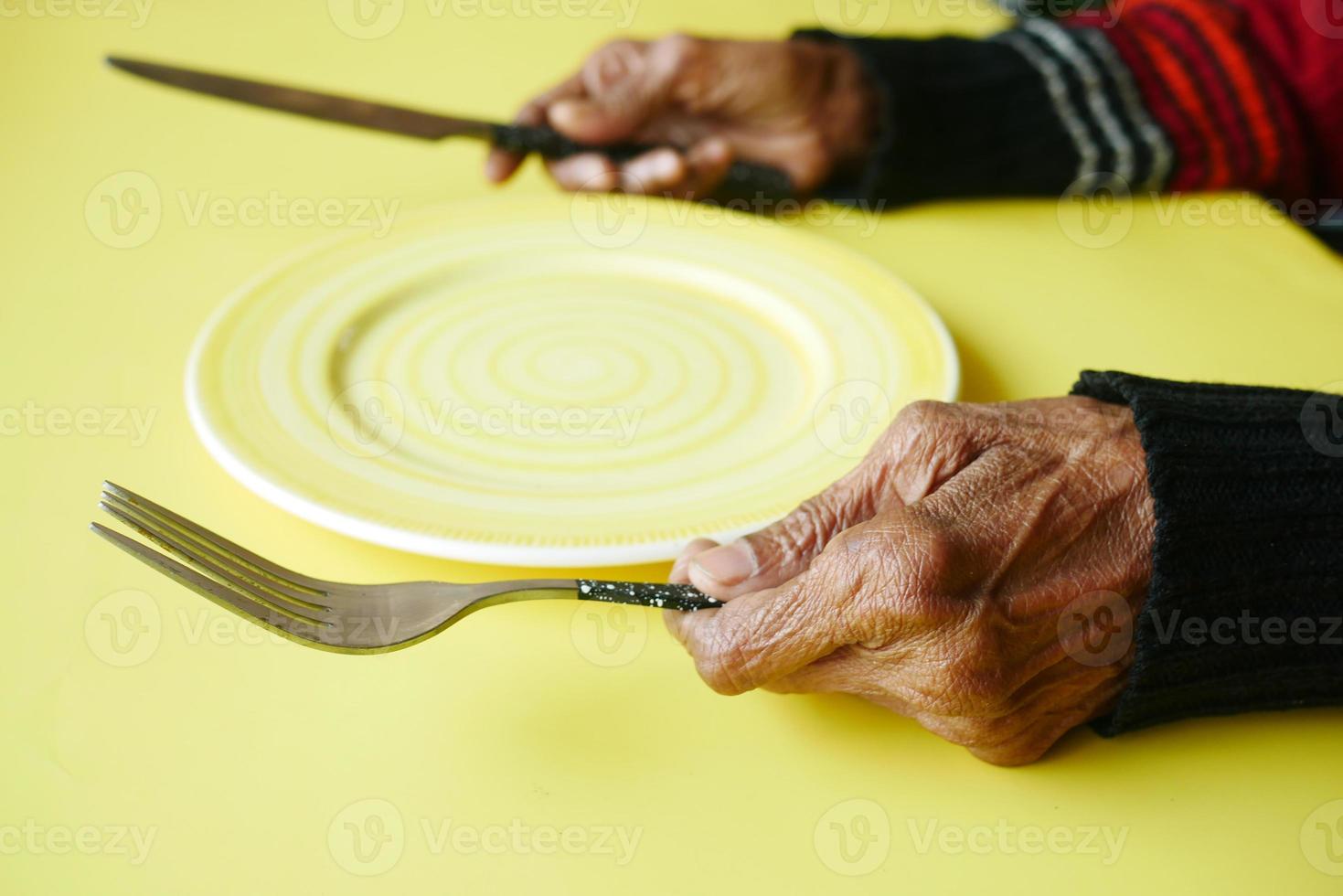 mujeres mayores sosteniendo cubiertos con plato vacío sobre fondo amarillo foto