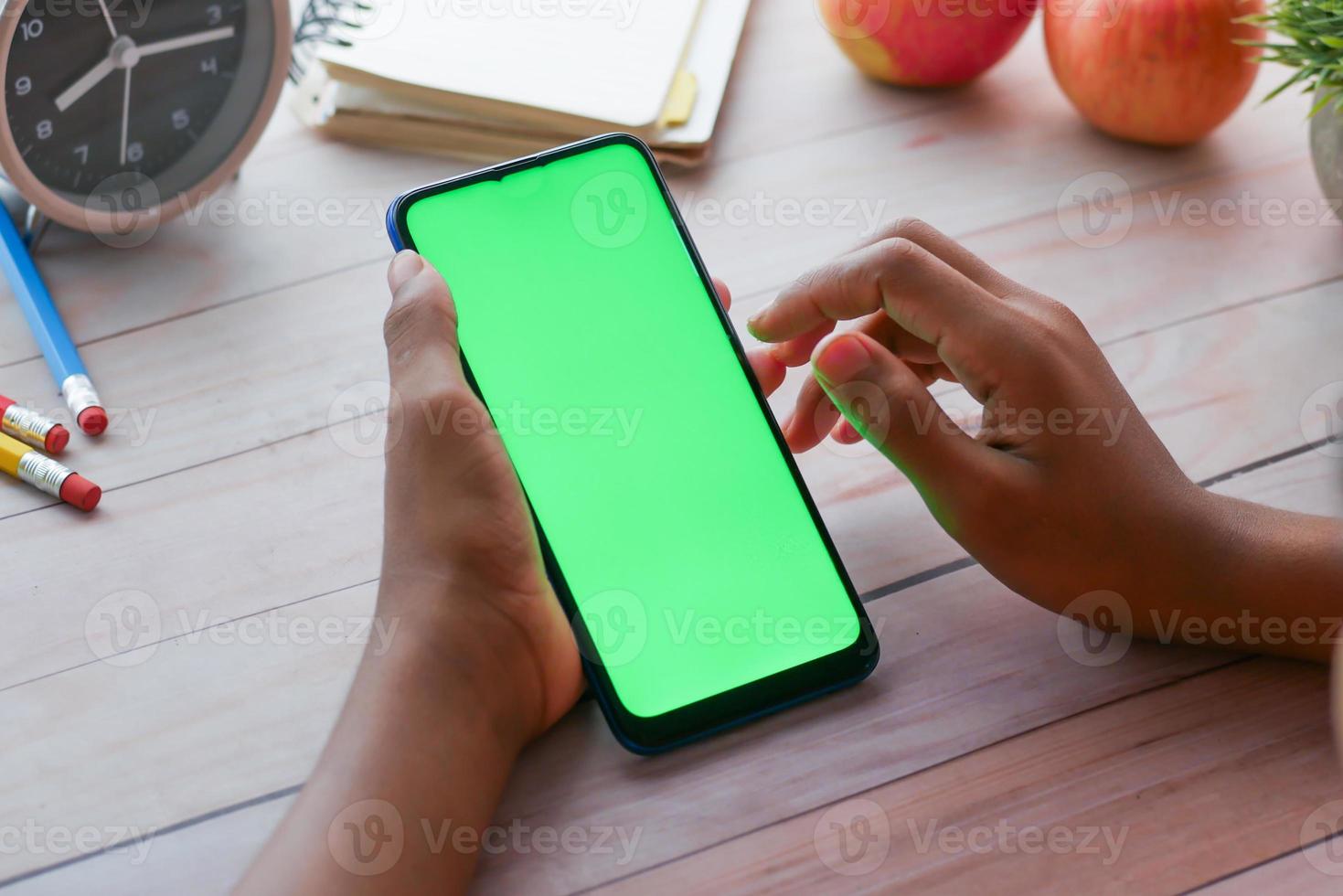 rear view of child hand holding smart phone with green screen photo