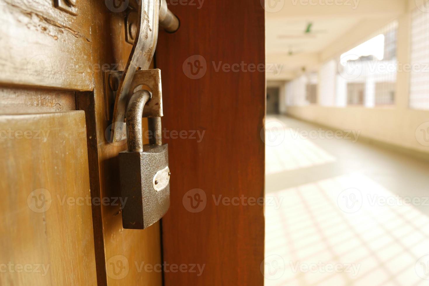 a padlock hanging on a door with empty corridor photo