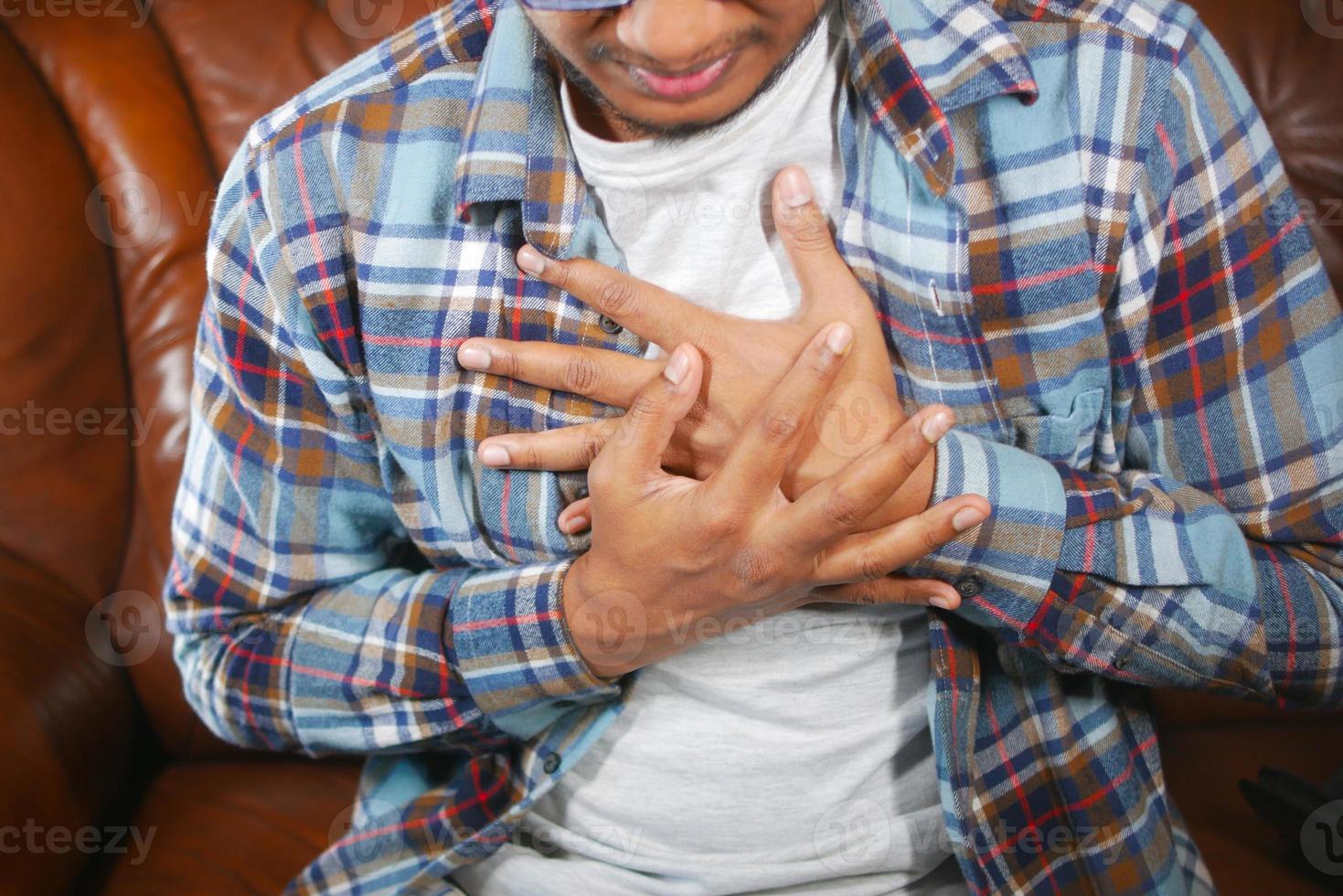 young man suffering pain in heart and holding chest with hand photo